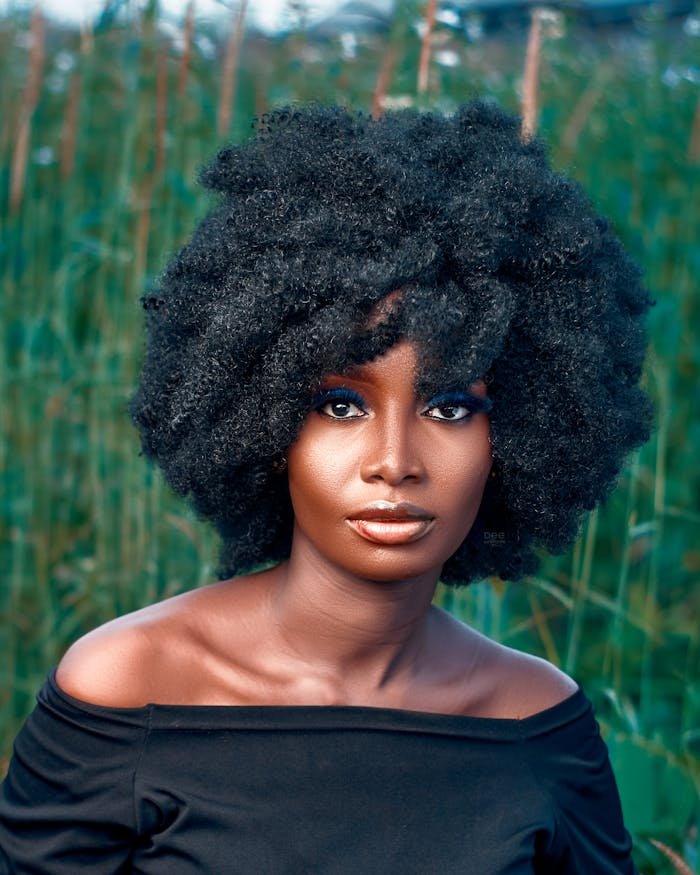 Elegant portrait of a young woman with afro hair posing outdoors, showcasing style and beauty.
